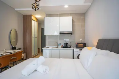 a bedroom with a white bed and a kitchen at Wyndham Garden Suites IPOH ICC in Ipoh