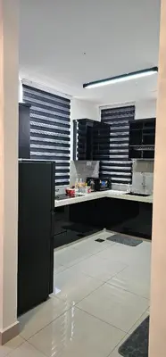 a kitchen with black cabinets and white counter tops at Suria Aman Homestay Semi-D 5 Rooms 5 Bathrooms in Taiping