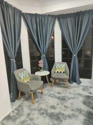 two chairs and a table in a room with blue curtains at Rania Homestay Tasek Gelugor in Padang Chempedak