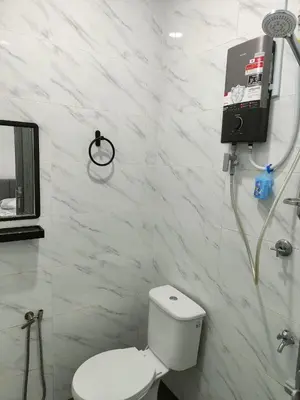 a white bathroom with a toilet and a shower at Rania Homestay Tasek Gelugor in Padang Chempedak
