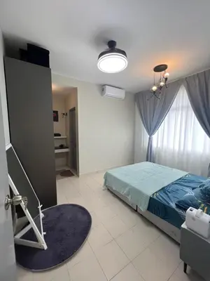 a bedroom with a bed with a blue comforter and a window at SweetHome in Ipoh