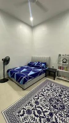 a bedroom with a bed with a blue comforter and a rug at D Cahaya Homestay in Tapah