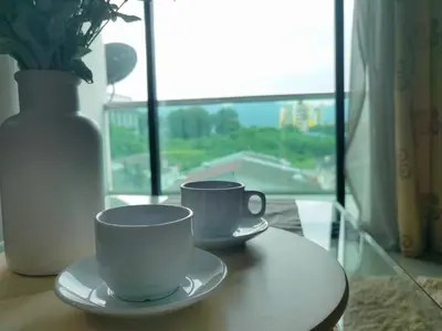 two coffee cups sitting on a table with a vase at Kinta Riverfront Apartment Ipoh, Fully Air-Con Suite IPOH in Ipoh