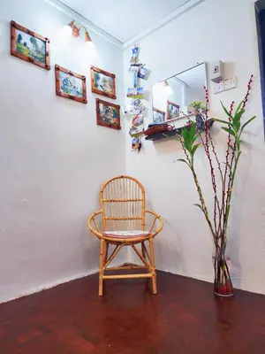 a chair sitting next to a white wall with a mirror at IPOH Taman Pelangi Double Storey Homestay in Ipoh