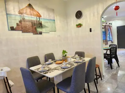 a dining room with a white table and chairs at IPOH Taman Pelangi Double Storey Homestay in Ipoh