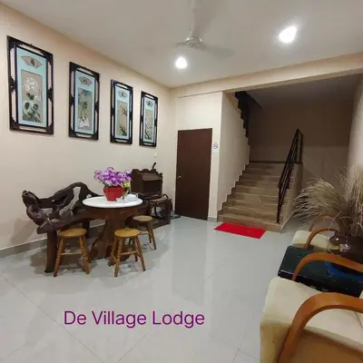 a living room with a table and chairs and stairs at De Village Lodge in Balik Pulau