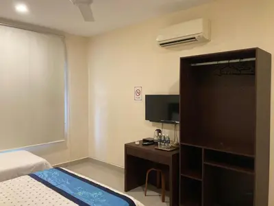 a bedroom with a bed and a tv and a desk at De Village Lodge in Balik Pulau
