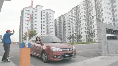 a man standing next to a red car in a parking lot at Jwa Vacastay in Lumut
