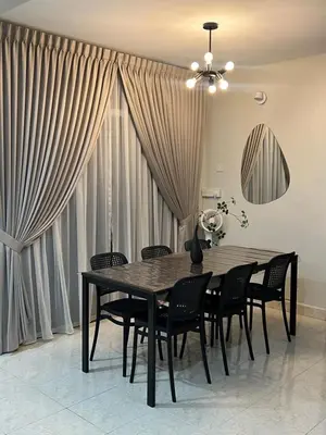 a dining room with a table and chairs and curtains at Cozy Stay Bertam in Kepala Batas