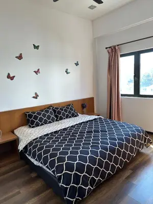 a bedroom with a bed with a blue comforter and a window at Nova Highlands Hilltop Retreat Cameron Highlands in Brinchang
