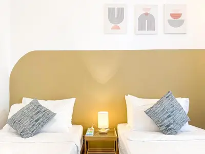 two beds with white pillows in a hotel room at Panoramic Georgetown City & Sea View with Netflix in Jelutong