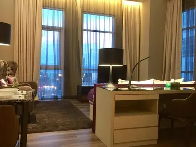 a living room with windows and a table with a lamp at Big BathTub Premium Seafront Studio in Town with WiFi & Full Kitchen in George Town