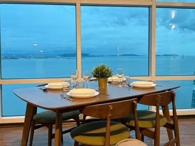 a wooden table with chairs and wine glasses at Seaview Seafront Duplex in Town with WiFi & Full Kitchen 16 in George Town