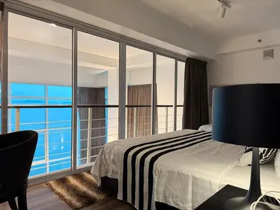 a bedroom with a bed and a view of the ocean at Seaview Seafront Duplex in Town with WiFi & Full Kitchen 16 in George Town