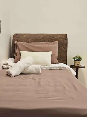 a bed with two white pillows and a brown blanket at Brickyard at 6 in Ipoh