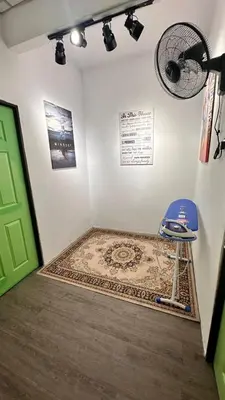 a room with a blue chair and a rug and a fan at Raintown House in Taiping
