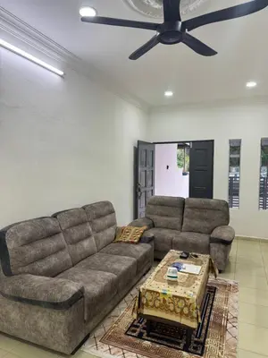a living room with two couches and a ceiling fan at Wika Homestay in Lunas