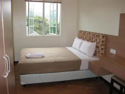 a small bedroom with a bed with a window at Golf View Apartment in Brinchang in Tanah Rata