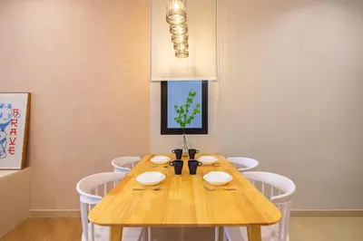 a dining room with a wooden table and white chairs at Iconic Regency by Stellar ALV in Bayan Lepas