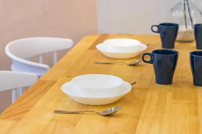 a wooden table with two white bowls and blue cups at Iconic Regency by Stellar ALV in Bayan Lepas
