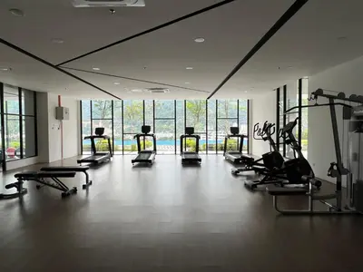 a gym with several treadmills and ellipticals in a room with windows at Sunshine Residence in Ayer Itam