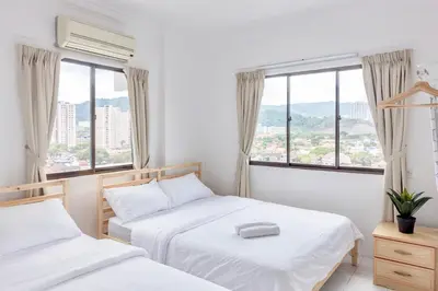 two beds in a room with two windows at Eastern Apt, Jelutong in Jelutong