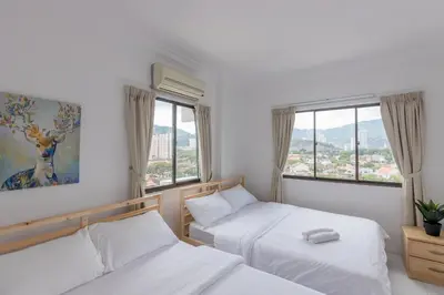 two beds in a room with two windows at Eastern Apt, Jelutong in Jelutong