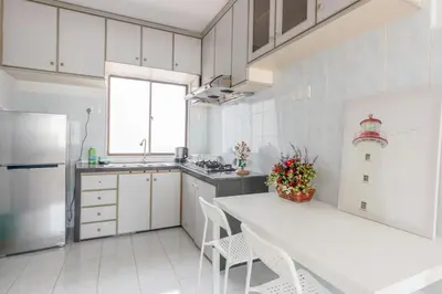 a white kitchen with a table and a refrigerator at Eastern Apt, Jelutong in Jelutong