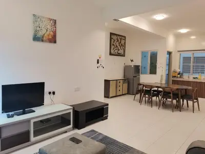 a living room with a tv and a table with chairs at Ummus Homestay in Tanah Rata