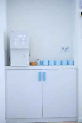 a kitchen with white cabinets and a microwave and blue cups at Tung Kidcove Centrum Cameron in Brinchang