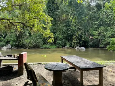 a picnic table and bench next to a river at Camp Site in Tapah