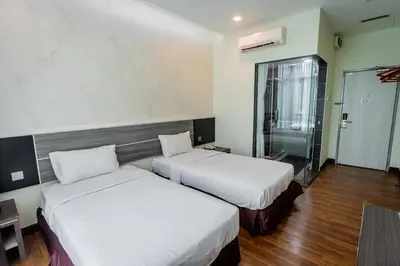 a hotel room with two beds and a glass door at Indra Hotel Ipoh in Ipoh
