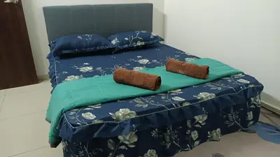 a bed with blue sheets and two brown pillows at D'SARRA Homestay Nibong Tebal in Nibung Tebal