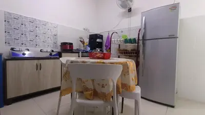 a kitchen with a table and a refrigerator at D'SARRA Homestay Nibong Tebal in Nibung Tebal