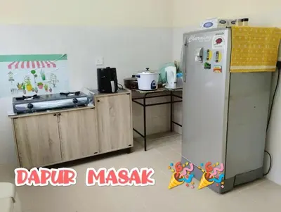 a small kitchen with a refrigerator and a table at Zunnurain Homestay in Kampong Batu Lapan