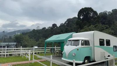 an rv with a tent parked in a field at The Starry Campervans Cameron Highlands in Cameron Highlands
