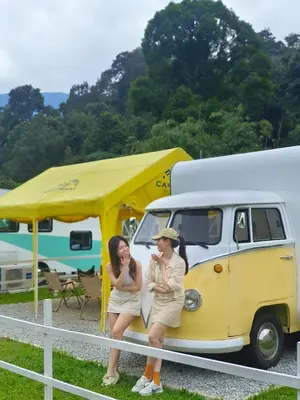two women standing next to a yellow and white van at The Starry Campervans Cameron Highlands in Cameron Highlands