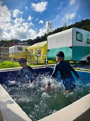 two boys playing in the water in a swimming pool at The Starry Campervans Cameron Highlands in Cameron Highlands