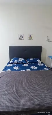 a bed with a blue comforter with white flowers on it at Aflah Home in Tapah Road