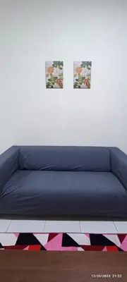 a blue couch in a room with two pictures on the wall at Aflah Home in Tapah Road