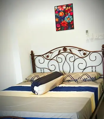 a bed with a metal headboard and a painting on the wall at Classic Spot - Meru Raya in Ipoh