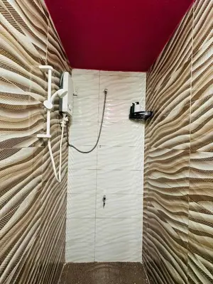 a bathroom with a white wall with a shower at M&M Bendi Homestay in Lunas