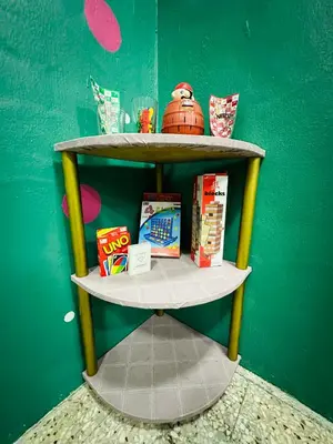 a shelf with toys and books on a green wall at M&M Bendi Homestay in Lunas