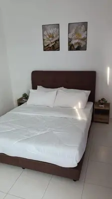 a bed in a bedroom with two pictures on the wall at KhyraHomestay in Kampong Ayer Melintas Besar