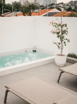 a plant in a pot on a balcony with a tub at Romantic Rooftop Jacuzzi Villa with Sunset Views in Jelutong