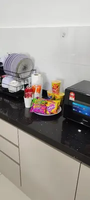 a counter top with a microwave and some food at DeRose Homestay, Pekan Ipoh in Ipoh