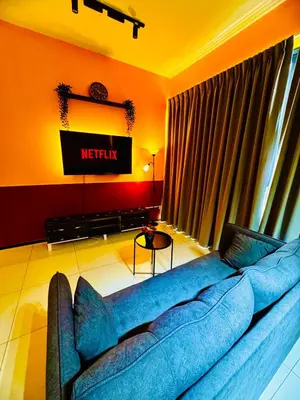 a living room with a blue couch and a television at Stunning Sea & City View Apartment in George Town in Jelutong