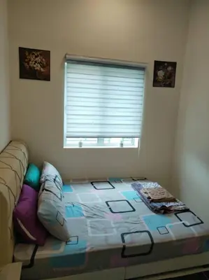 a bedroom with a bed and a window with a window blindiosyn at A to Z Homestay in Sitiawan