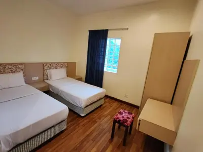 a room with two beds and a chair and a window at Iris House Resort & Apartment Cameron Highlands in Cameron Highlands