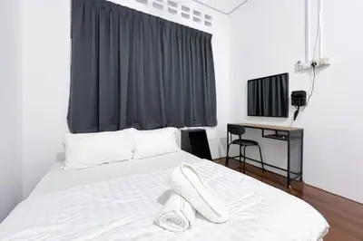 a bedroom with a bed with white sheets and a desk at Homestay Taman Canning Ipoh, Perak - Smarthome in Ipoh